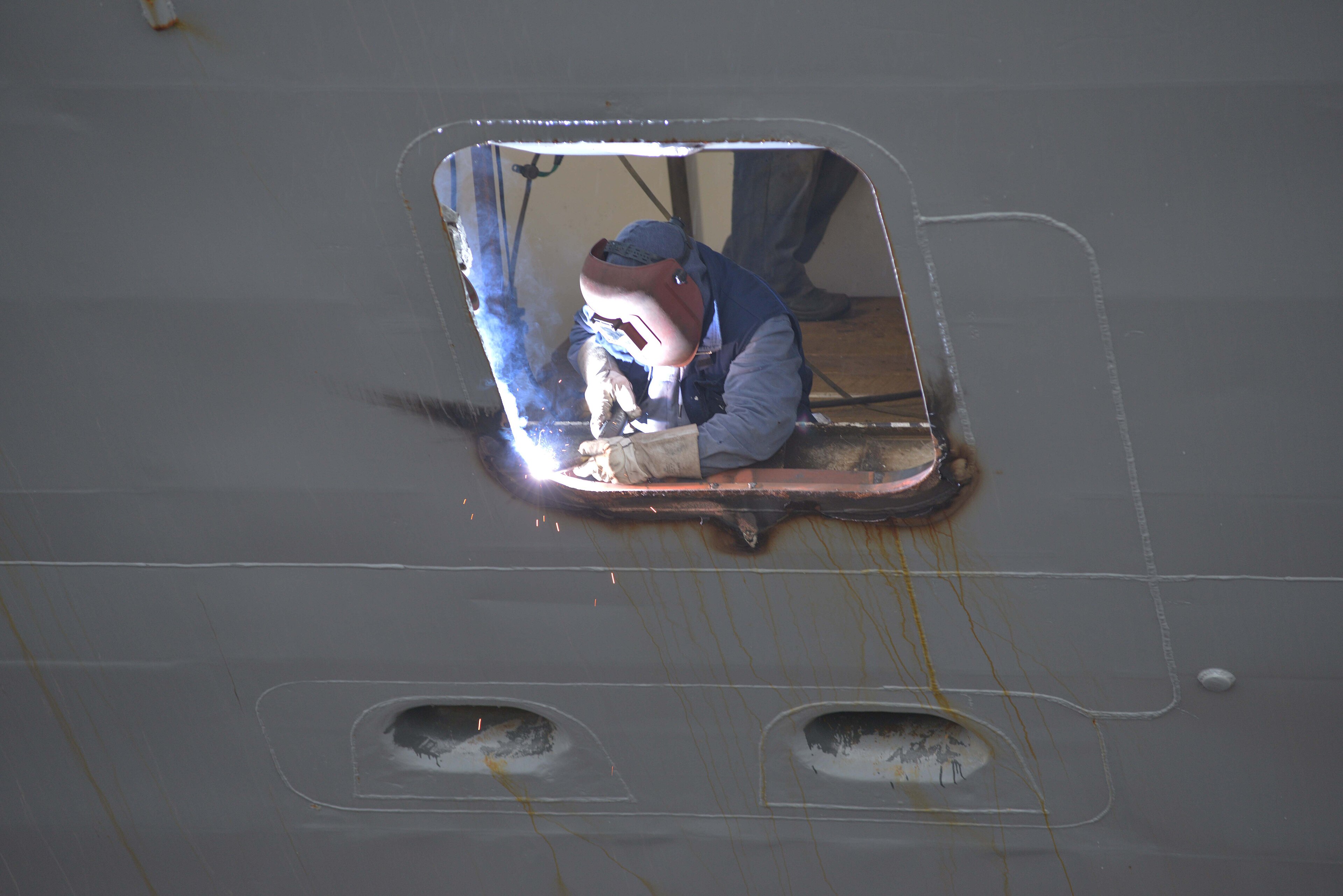 Soldador trabalhando em abertura no costado de um navio